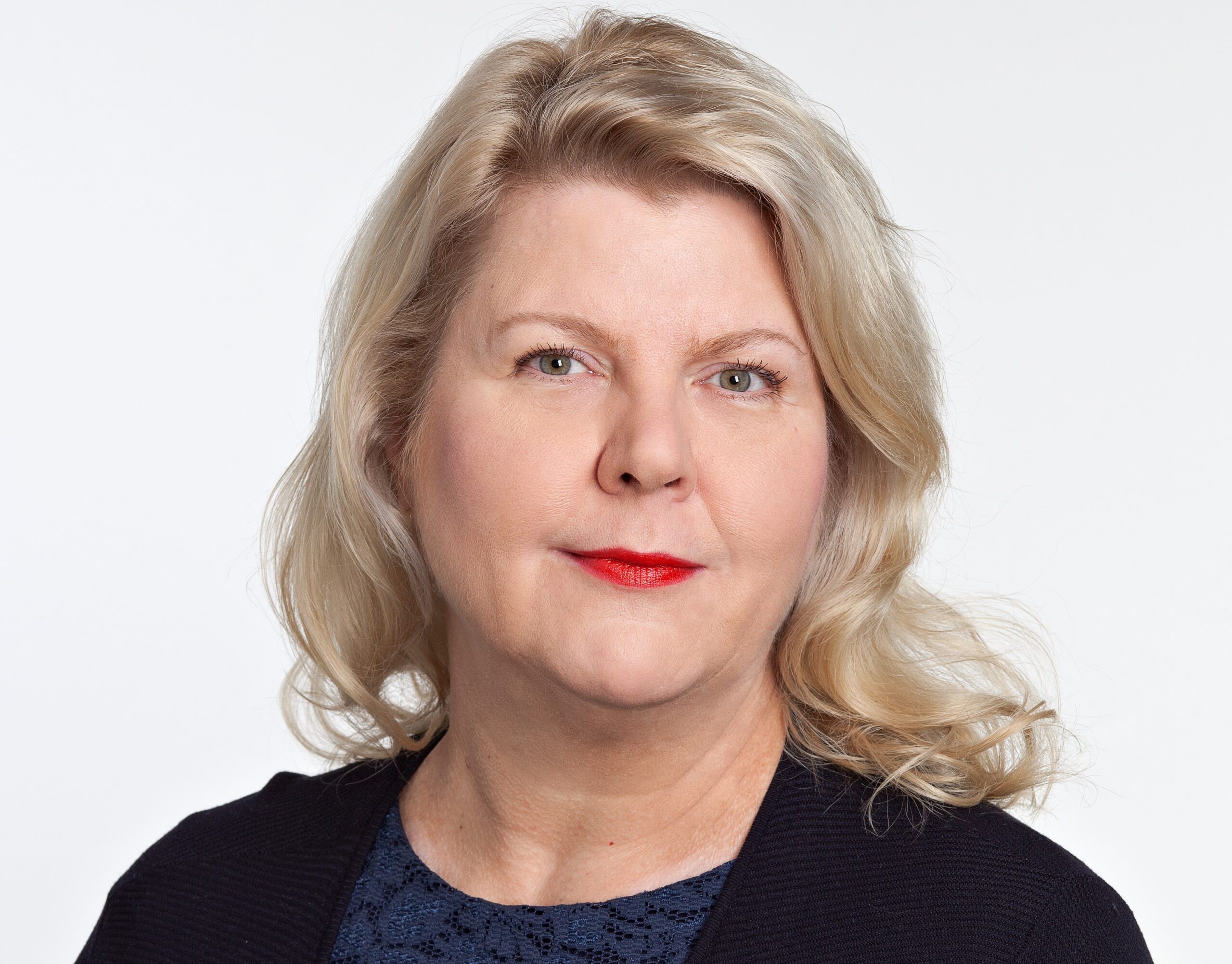 Kasvokuvassa vaaleatukkainen, vakavailmeinen tummaan asuun pukeutunut nainen.