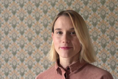 Kasvokuvassa lohenvärinsee kauluspaitaan pukeutunut polkkatukkainen, vaaleahiuksinen nainen.
