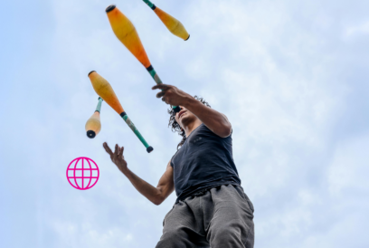 Nuori miesoletettu jonglöörää vaaleansinistä taivasta vasten.